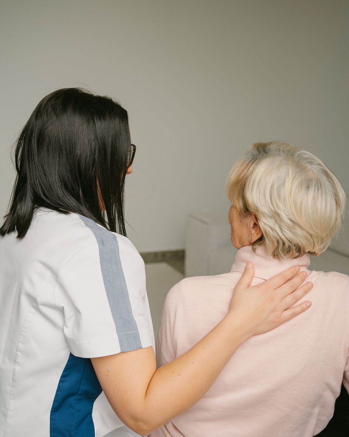 Thuisverpleegkundige met een hand op de schouder van een oudere patiënte
